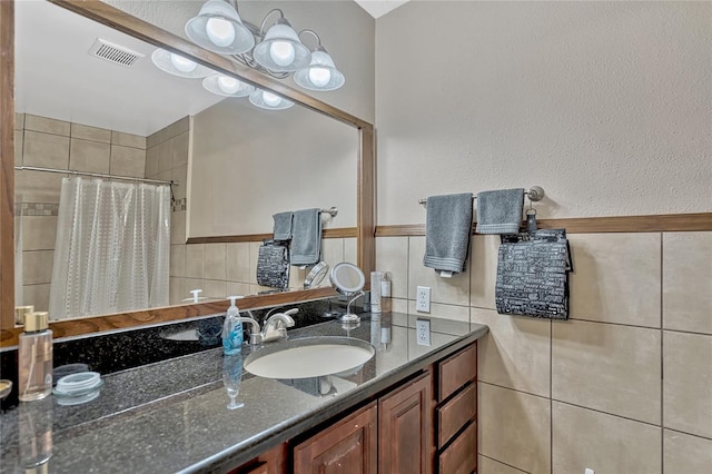 full bathroom with visible vents, tile walls, vanity, and a tile shower