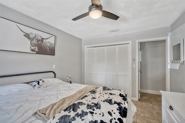 bedroom featuring visible vents, a closet, light tile patterned flooring, baseboards, and ceiling fan