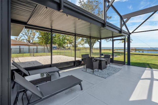 view of patio with a lanai, fence, and a water view