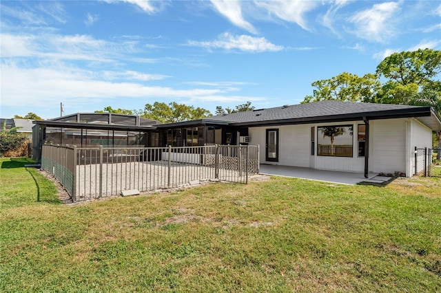 rear view of house with a patio area, glass enclosure, a yard, and fence