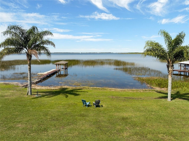 view of dock with a lawn and a water view