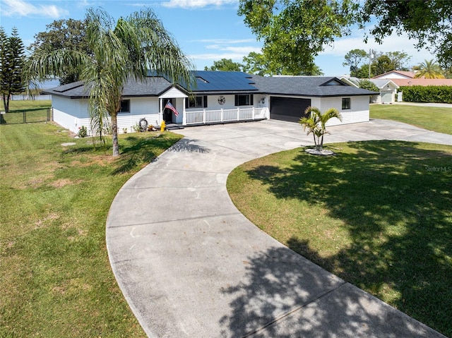 single story home with a front lawn, roof mounted solar panels, a porch, concrete driveway, and a garage