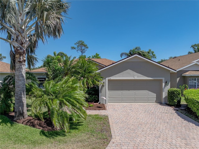 ranch-style house featuring decorative driveway, stucco siding, and an attached garage