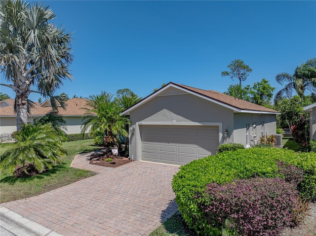 view of property exterior featuring driveway, stucco siding, central air condition unit, and an attached garage