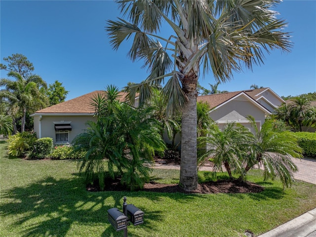 view of property exterior with stucco siding, a shingled roof, and a lawn