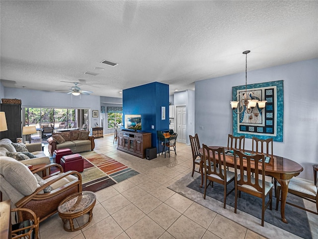 living room featuring light tile patterned floors, visible vents, a textured ceiling, and ceiling fan