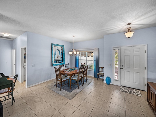 dining area with a textured ceiling, light tile patterned floors, baseboards, visible vents, and an inviting chandelier