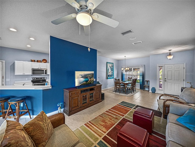 living area with light tile patterned flooring, a textured ceiling, visible vents, and a ceiling fan