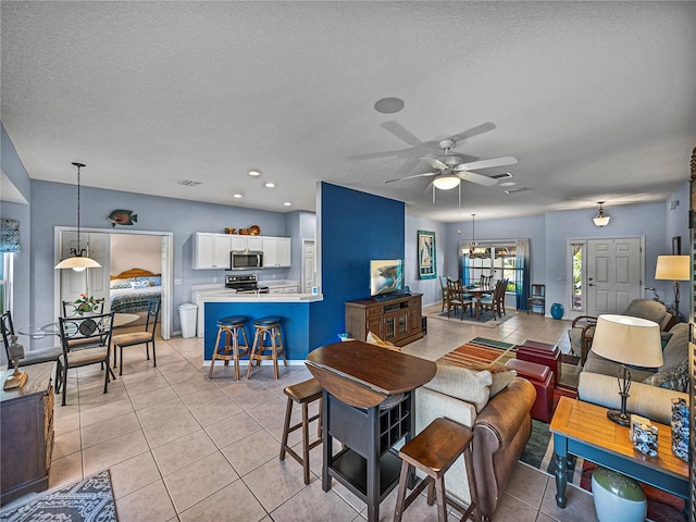 living area with light tile patterned flooring, a textured ceiling, visible vents, ceiling fan, and recessed lighting
