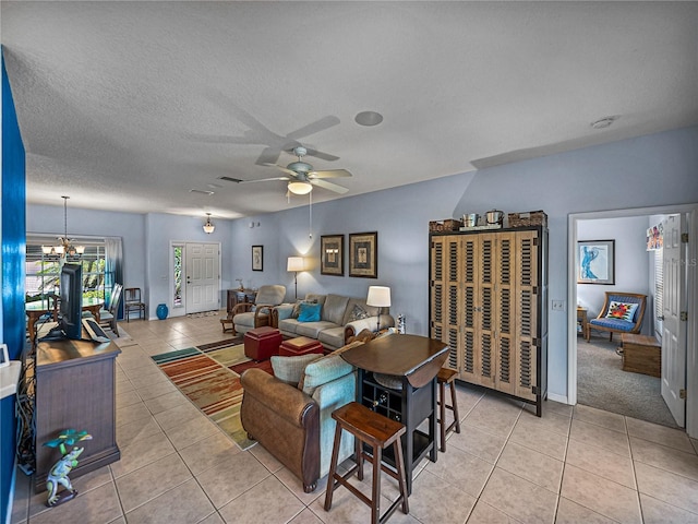 living area with a ceiling fan, light tile patterned floors, and a textured ceiling