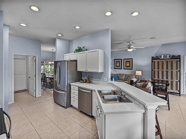 kitchen featuring light countertops, white cabinets, a peninsula, appliances with stainless steel finishes, and a sink