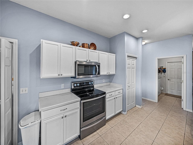 kitchen with light countertops, white cabinetry, appliances with stainless steel finishes, light tile patterned floors, and baseboards