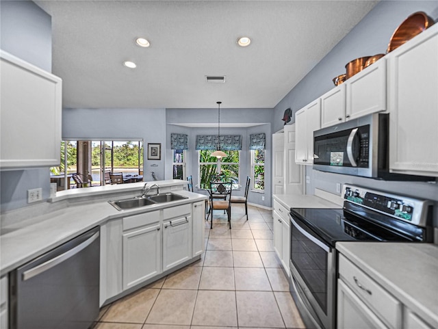 kitchen featuring light countertops, a sink, light tile patterned flooring, white cabinets, and appliances with stainless steel finishes
