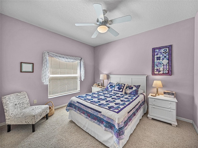 bedroom featuring baseboards, a textured ceiling, ceiling fan, and light carpet