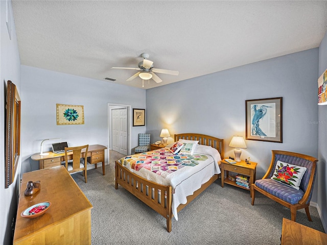 bedroom featuring a closet, light carpet, a textured ceiling, visible vents, and ceiling fan