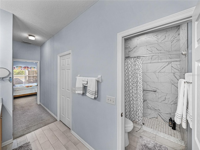 bathroom with a stall shower, connected bathroom, toilet, a textured ceiling, and baseboards