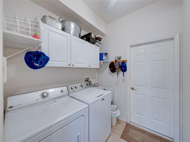 laundry room with washer and clothes dryer, cabinet space, and light tile patterned floors