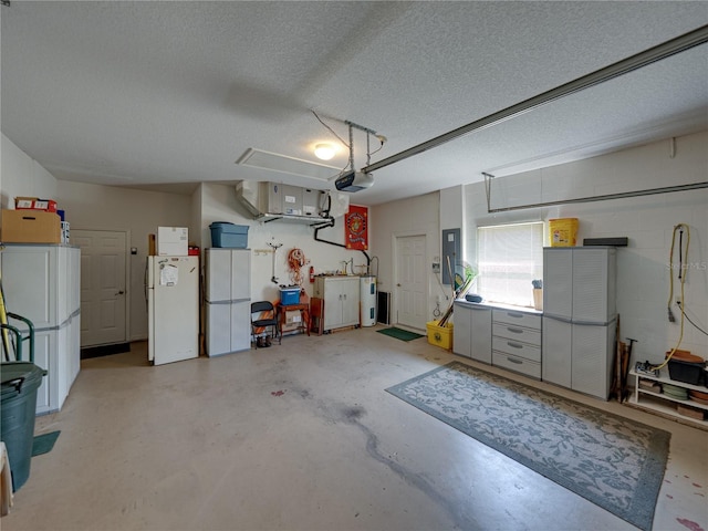 garage featuring water heater, concrete block wall, electric panel, and freestanding refrigerator