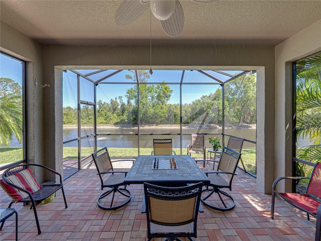sunroom with a water view, ceiling fan, and a healthy amount of sunlight