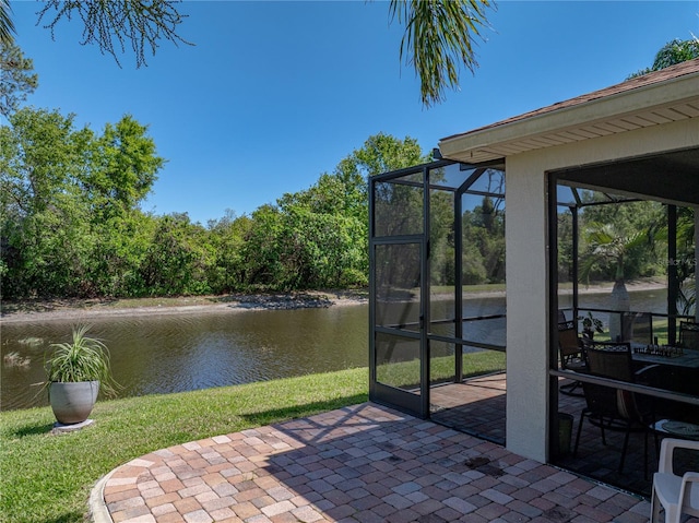 view of patio / terrace featuring glass enclosure and a water view