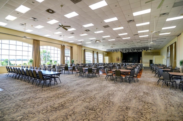 carpeted dining space with a paneled ceiling, a ceiling fan, and visible vents