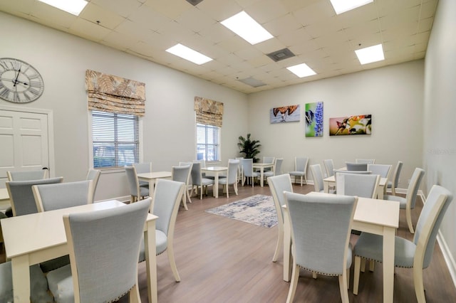dining area with visible vents, wood finished floors, and a paneled ceiling