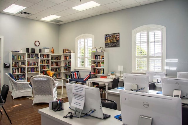office area with a drop ceiling, visible vents, and wood finished floors