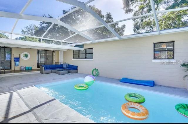 view of swimming pool featuring glass enclosure, an outdoor living space, and a patio