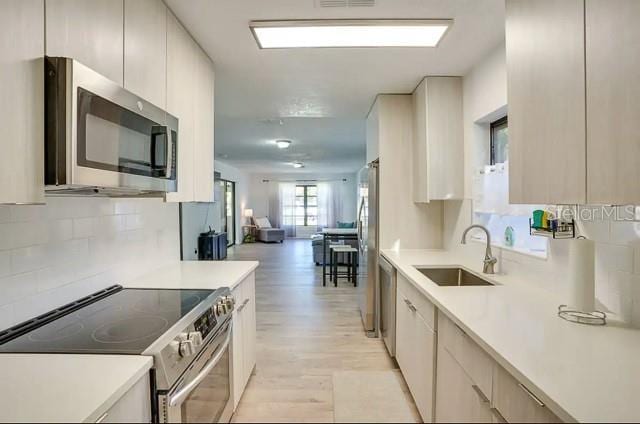 kitchen with open floor plan, stainless steel appliances, light countertops, and a sink