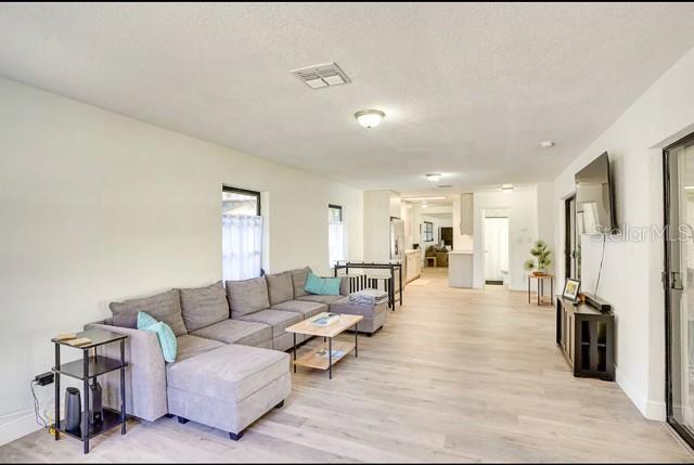 living room featuring visible vents, baseboards, and light wood-style floors