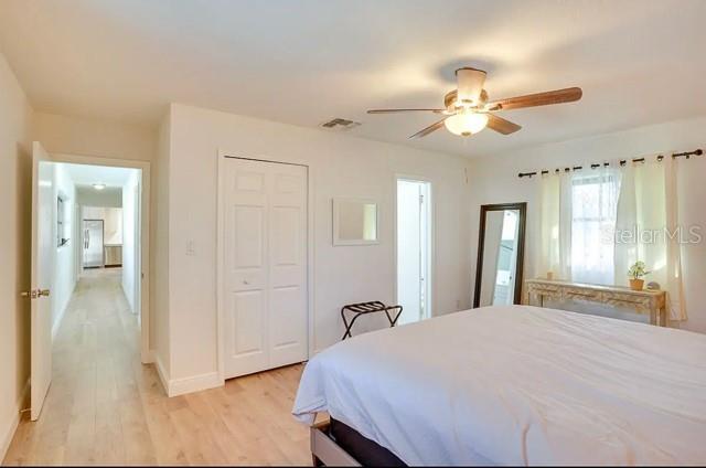 bedroom featuring a ceiling fan, visible vents, baseboards, light wood-style flooring, and a closet