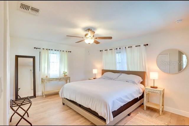 bedroom featuring a ceiling fan, light wood-style flooring, baseboards, and visible vents