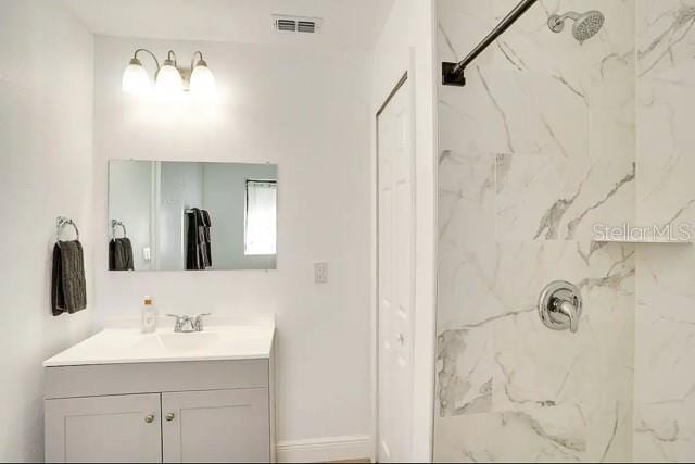 full bath with a marble finish shower, visible vents, and vanity