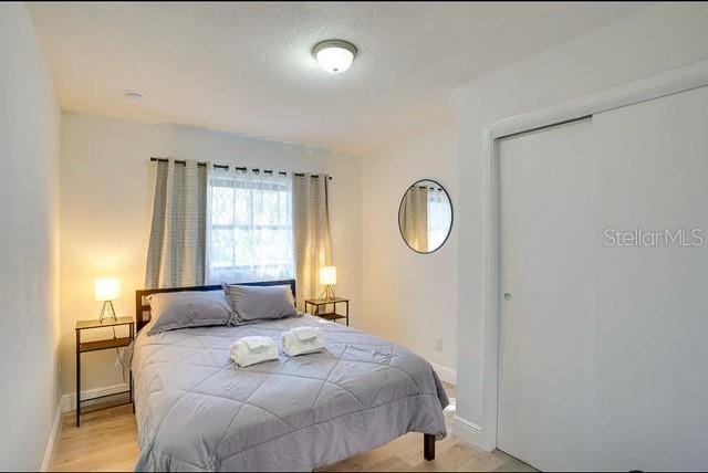 bedroom with a closet, baseboards, and light wood finished floors