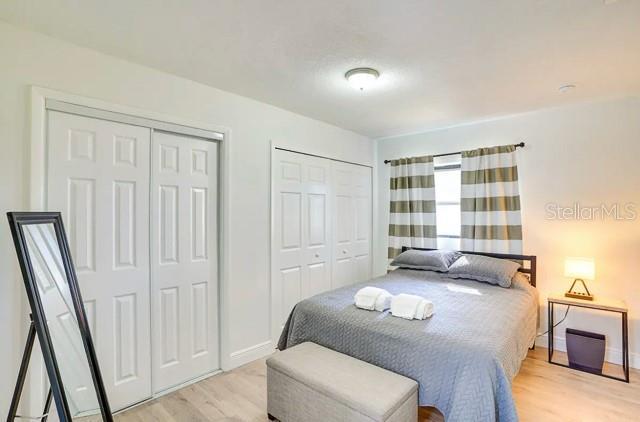 bedroom with light wood-type flooring, multiple closets, and baseboards