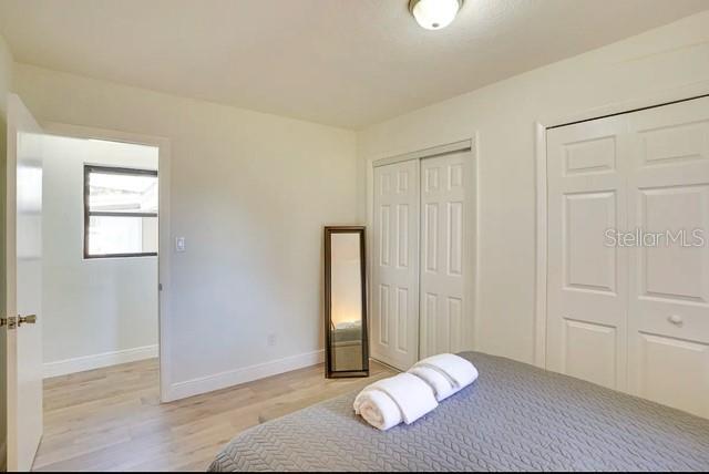 bedroom with light wood-type flooring, baseboards, and two closets