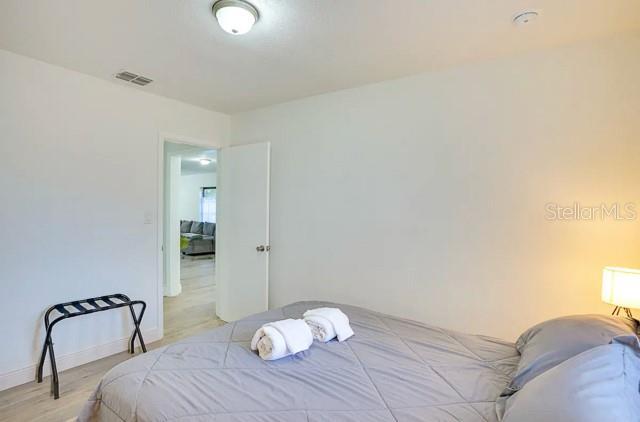 bedroom with light wood-style flooring, visible vents, and baseboards