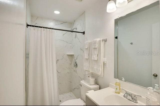 full bathroom featuring vanity, toilet, and a marble finish shower