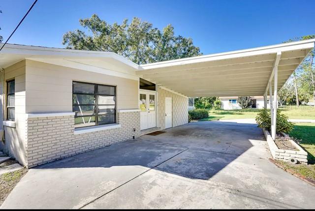 exterior space with a carport, concrete driveway, and brick siding