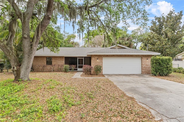 ranch-style home with a garage, brick siding, driveway, and a shingled roof