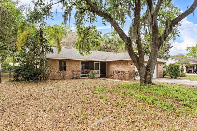 ranch-style home featuring driveway, brick siding, an attached garage, and fence