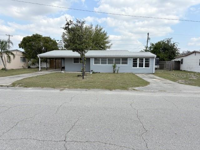 view of front of home with a carport, fence, a front lawn, and driveway