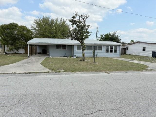 ranch-style home with driveway, an attached carport, and a front lawn