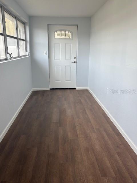 doorway with dark wood finished floors and baseboards