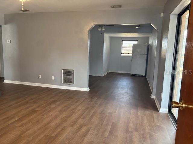 unfurnished room featuring baseboards, heating unit, arched walkways, a ceiling fan, and dark wood-style flooring