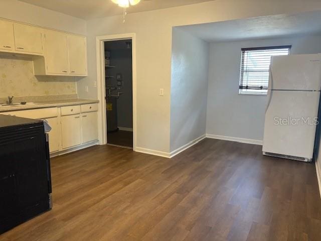 kitchen featuring baseboards, light countertops, freestanding refrigerator, dark wood-style floors, and white cabinets