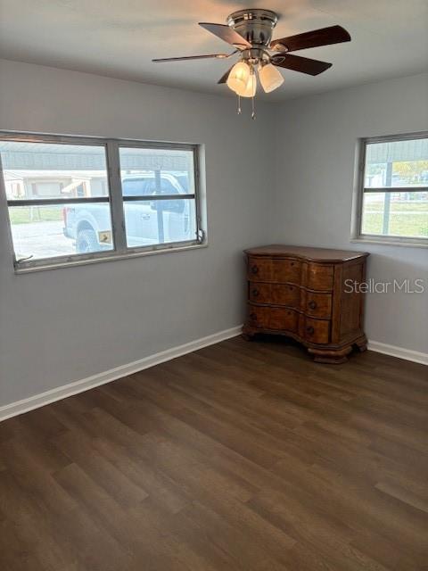 unfurnished room with a ceiling fan, baseboards, and wood finished floors