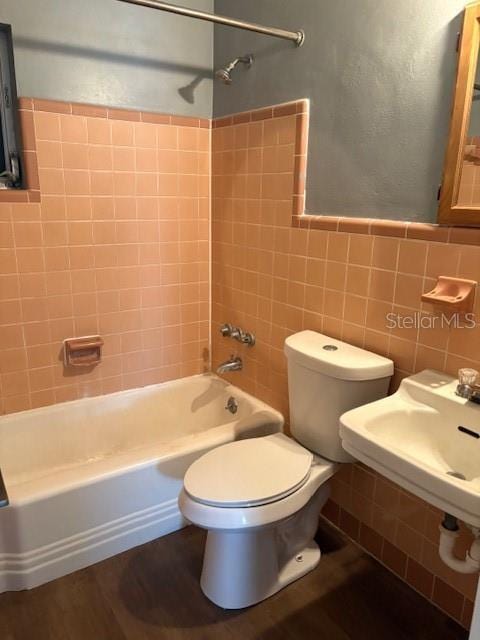 full bathroom with a wainscoted wall, toilet, shower / bath combination, wood finished floors, and tile walls