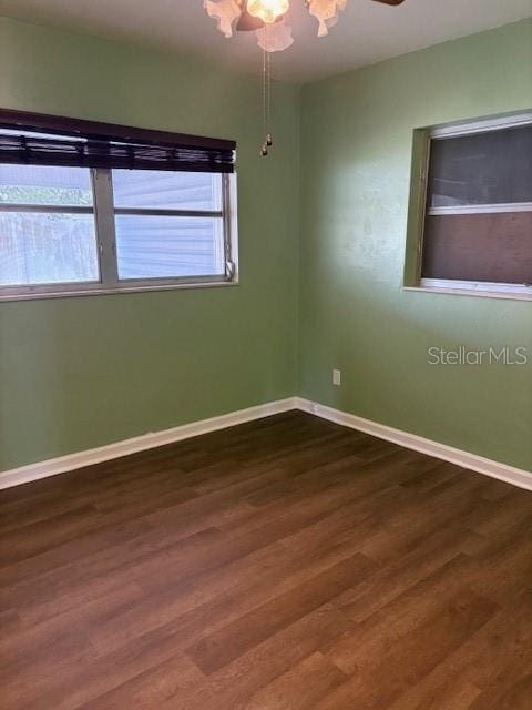 spare room with baseboards, a healthy amount of sunlight, and dark wood finished floors