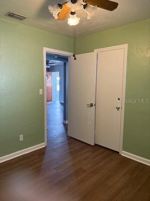 unfurnished room featuring a ceiling fan, wood finished floors, visible vents, and baseboards